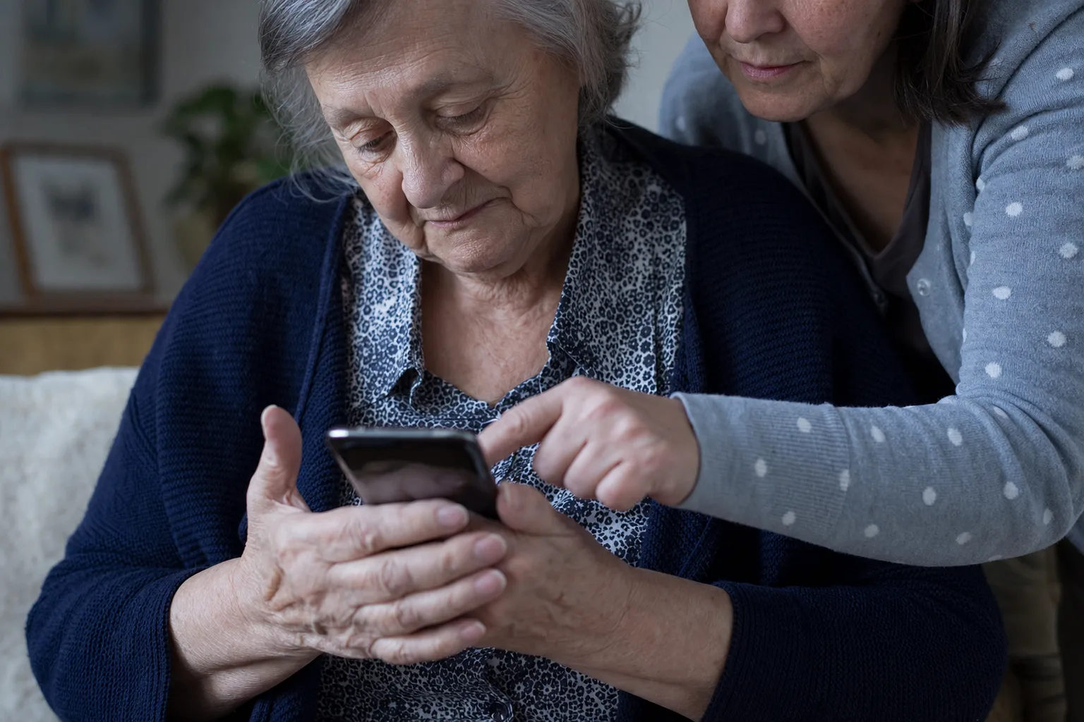 Dospělá dcera pomáhá své starší mamince s nastavením aplikace v mobilním telefonu